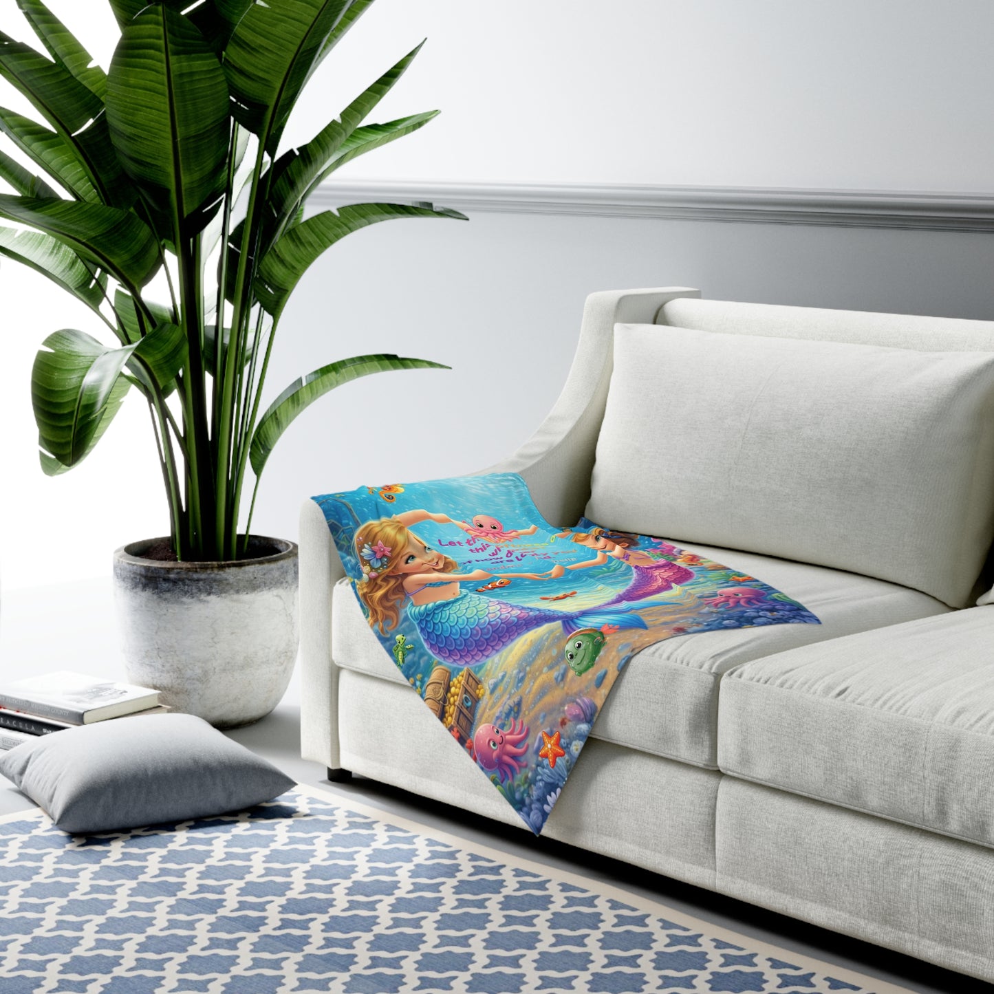 Colorful mermaid-themed blanket on a white couch with a plant and rug in the background