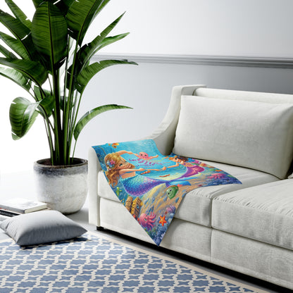 Colorful mermaid-themed blanket on a white couch with a plant and rug in the background