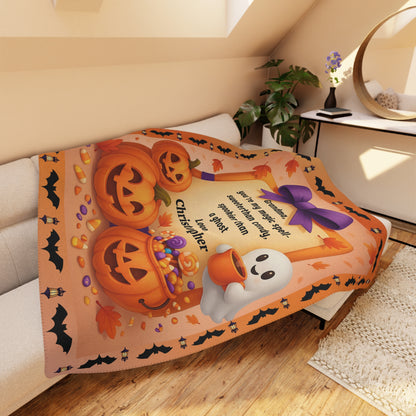 Halloween-themed blanket with pumpkins and ghosts on a bed in a room.